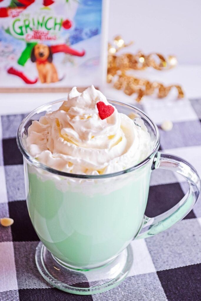 a cup filled with whipped cream on top of a checkered table cloth next to a book