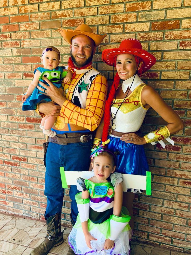 a man and woman in costume standing next to a brick wall with two small children