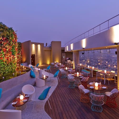 an outdoor dining area with tables and chairs, lit up by candles on the roof