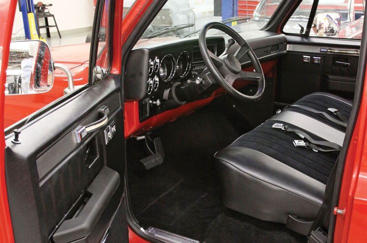 the interior of a red truck with black leather seats