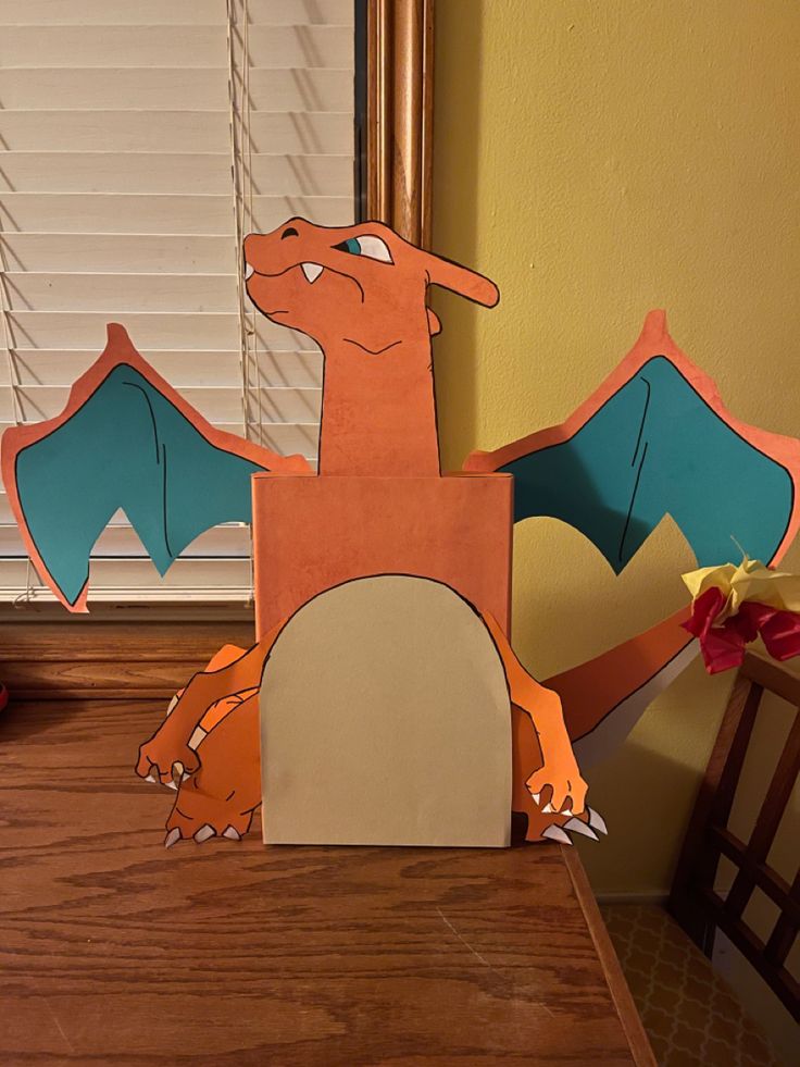 a paper cut out of a dragon sitting on top of a table next to a window