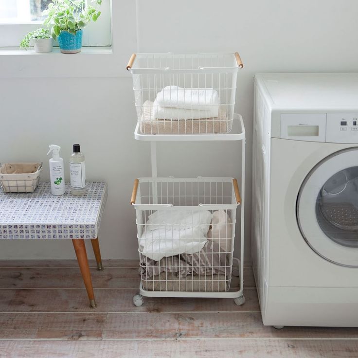 a washer and dryer in a small room next to a window with plants