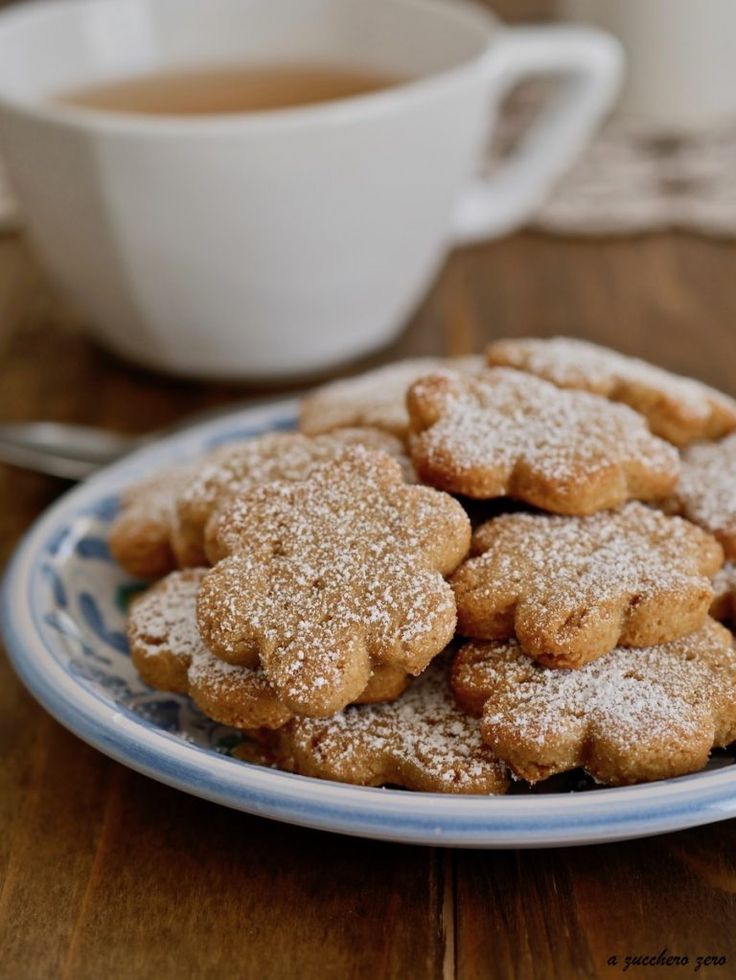 some sugar cookies are on a blue and white plate next to a cup of coffee