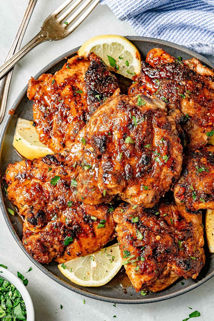 grilled chicken with lemons and herbs in a skillet on a white table