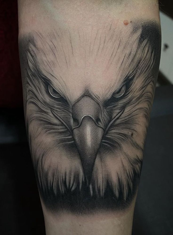 an eagle tattoo on the leg with black and grey ink, it looks like he's looking at something