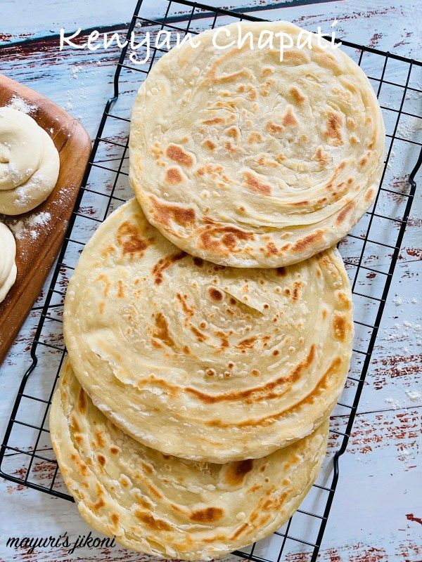 several flat breads are stacked on a cooling rack next to some doughnuts