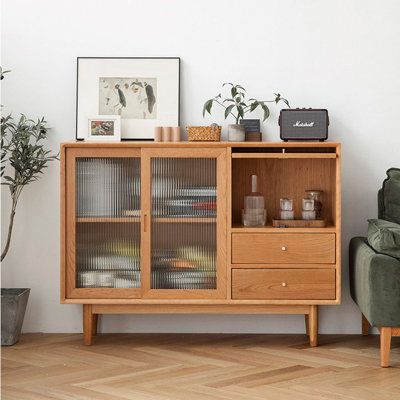 a wooden cabinet sitting next to a green chair in a living room with white walls