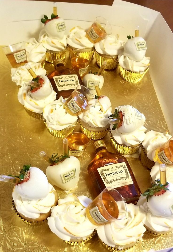 cupcakes with white frosting and strawberries are arranged on a gold tray