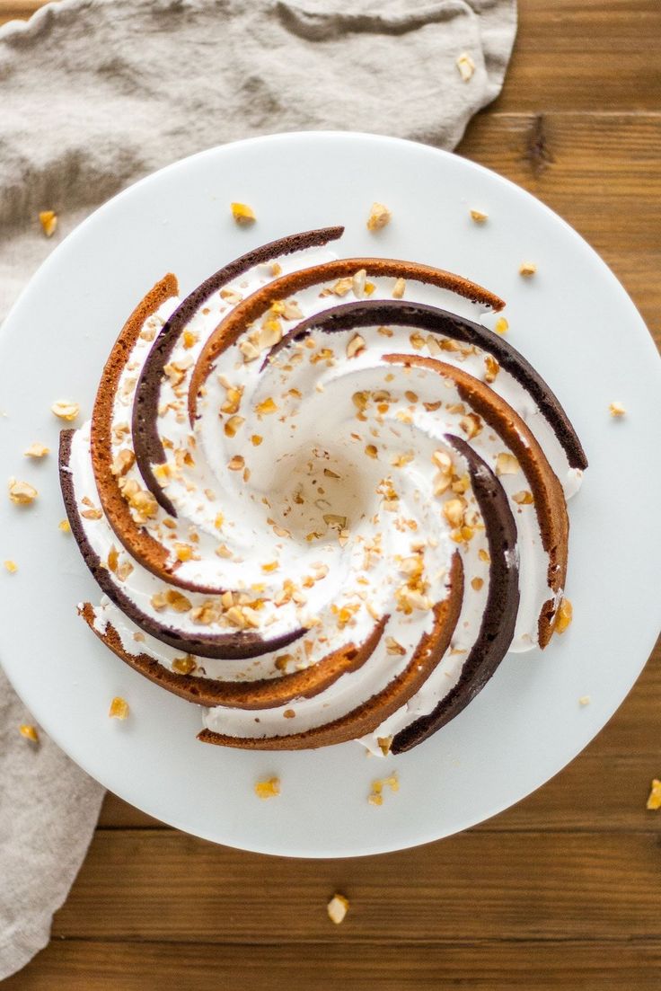 a white plate topped with cake covered in frosting and toppings on top of a wooden table