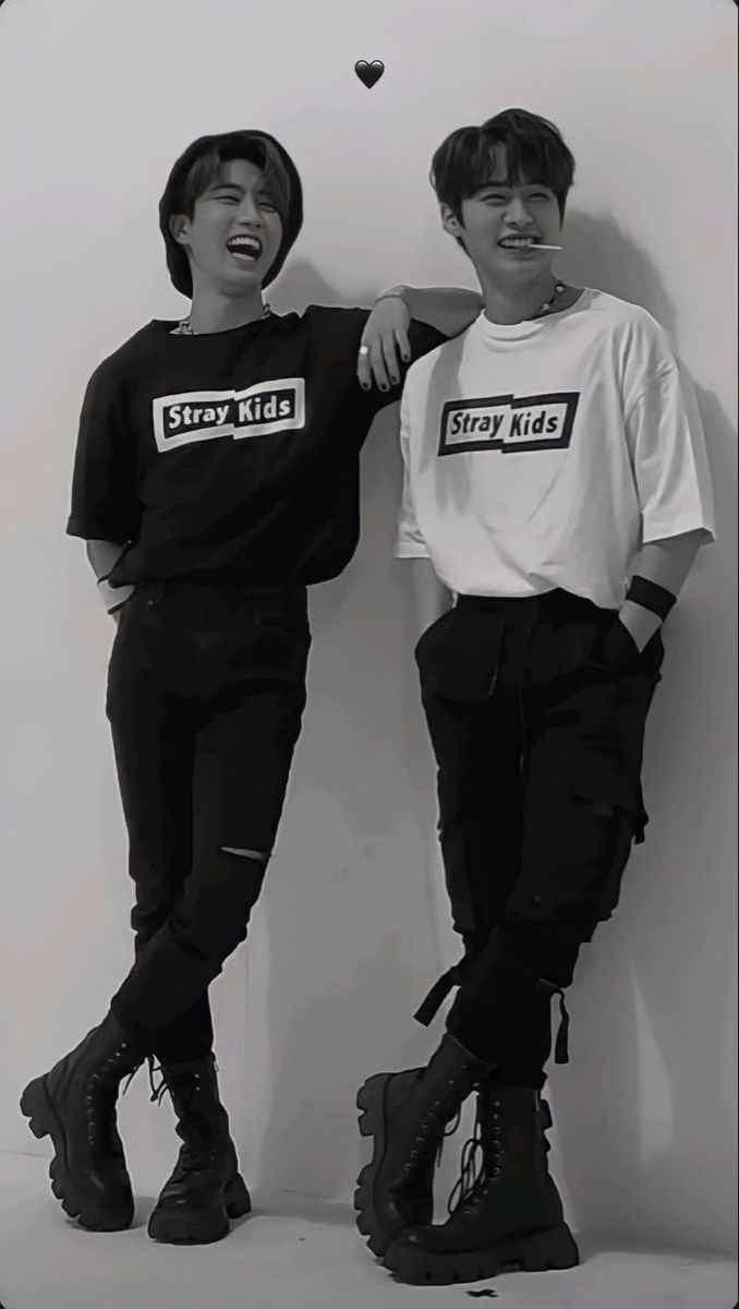 two young men standing next to each other in front of a white wall with the word stay kids on it