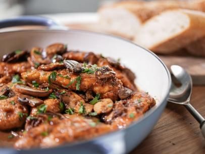 a close up of a bowl of food with bread in the background