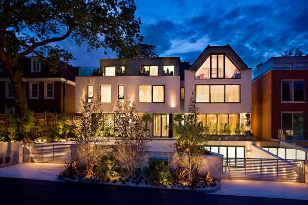 a large house lit up at night with lights on and trees in the front yard