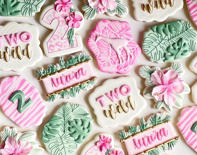 decorated cookies with pink, green and white frosting are arranged in the shape of numbers