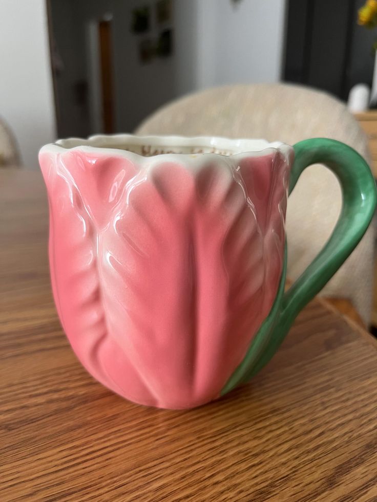 a pink and green coffee cup sitting on top of a wooden table