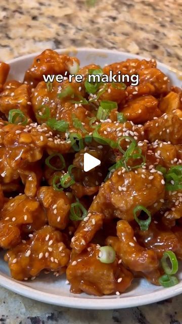 a white plate topped with chicken covered in sesame seeds