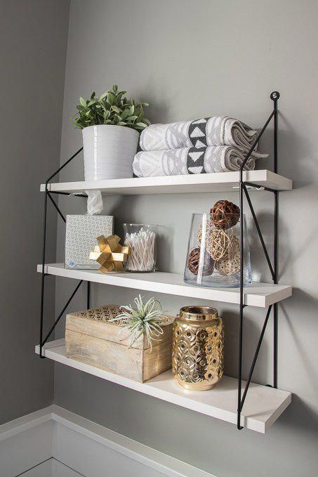 three shelves with towels, candles and other items on them in the corner of a room