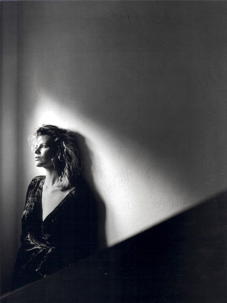 a black and white photo of a woman leaning against a wall with her head turned to the side