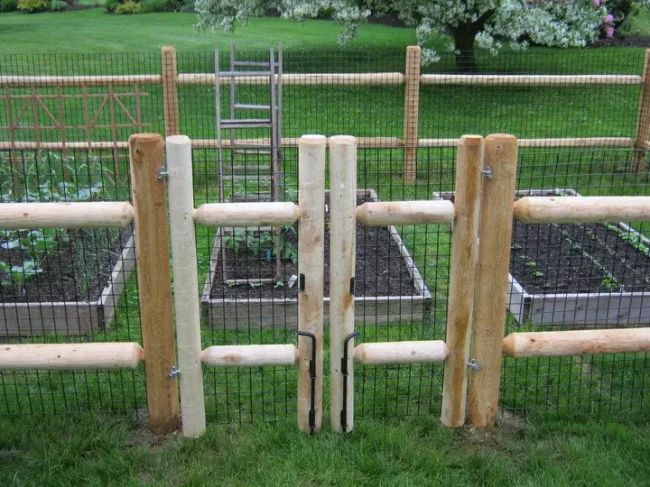 an outdoor garden with wooden posts and plants in the center, surrounded by green grass