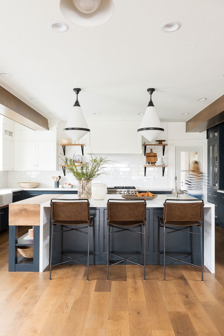 a kitchen island with four chairs and an island table in front of it, surrounded by blue cabinets