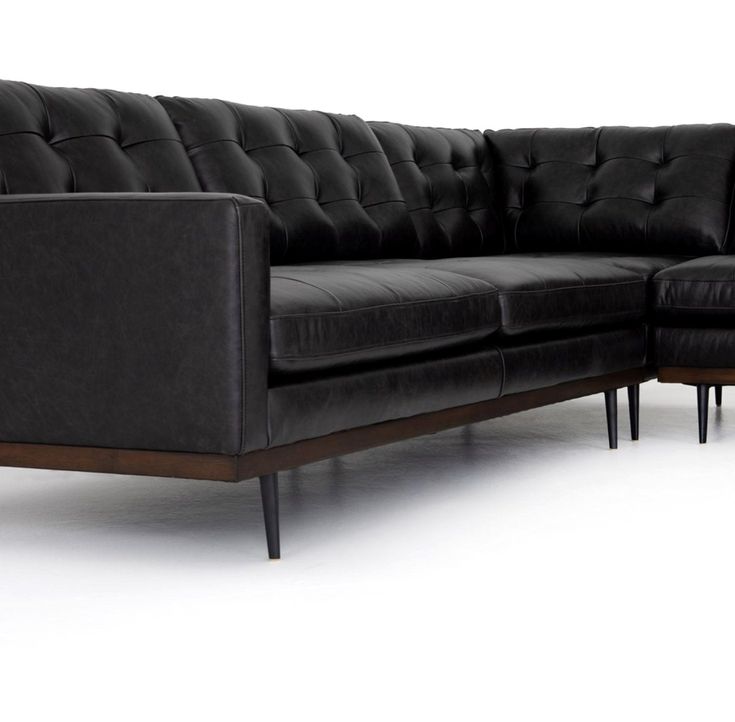 a black leather sectional sofa with wooden legs and footrests on an isolated white background