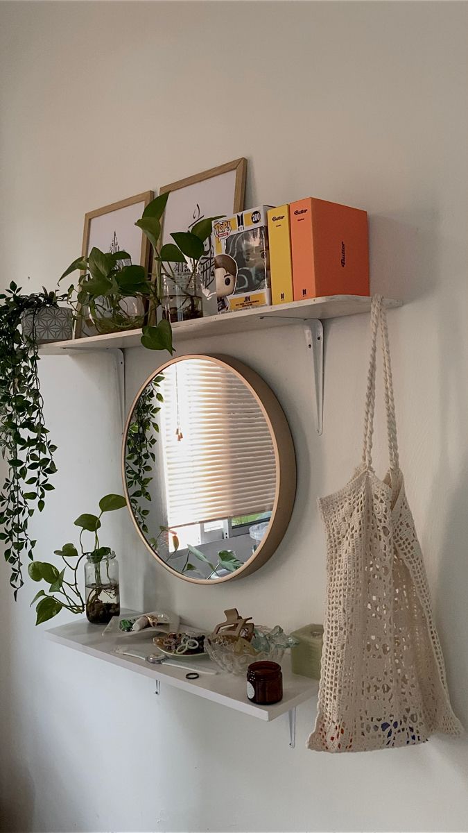 there is a mirror and some plants on the shelf next to each other in this room