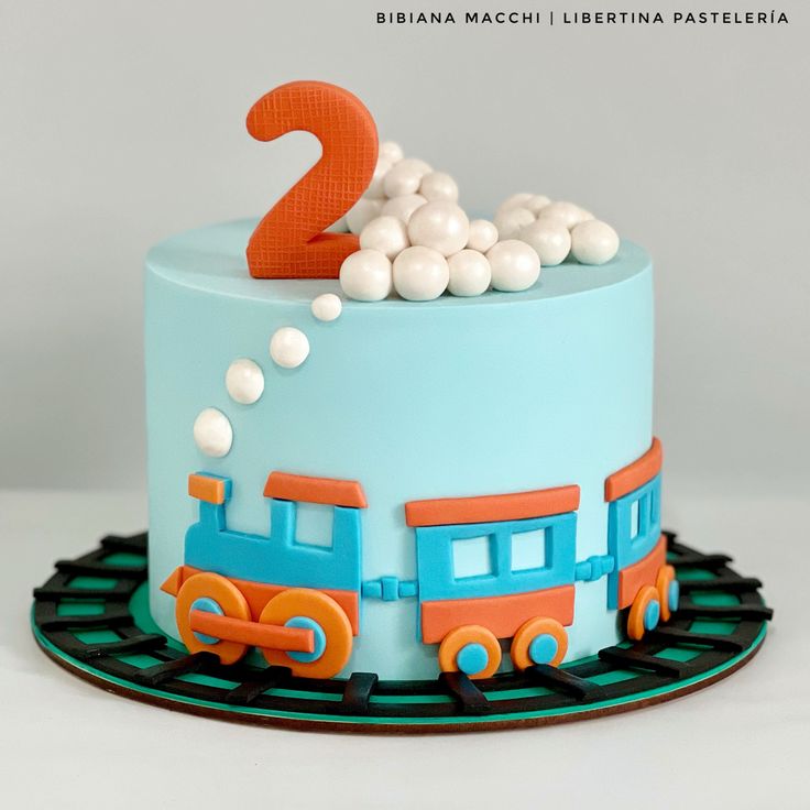 there is a cake that looks like a train with the number two on it and white balls