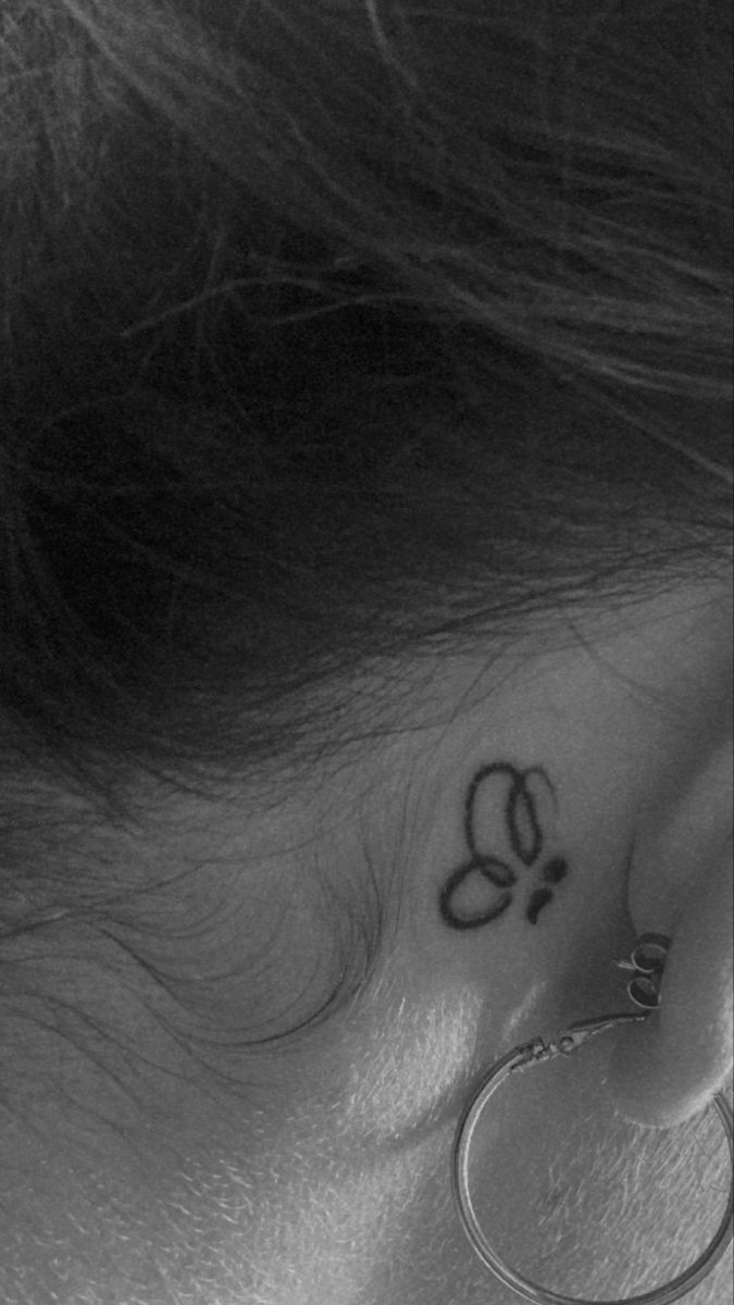 a woman's behind the ear has a butterfly tattoo on it