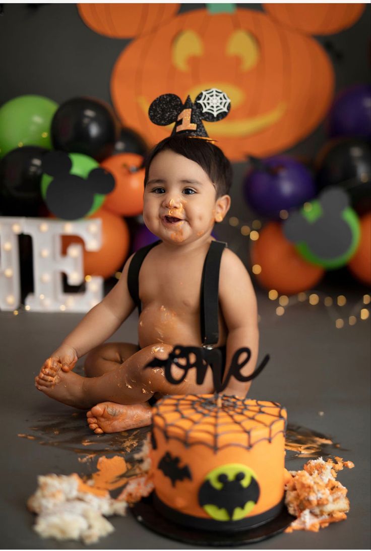 a baby sitting in front of a halloween cake