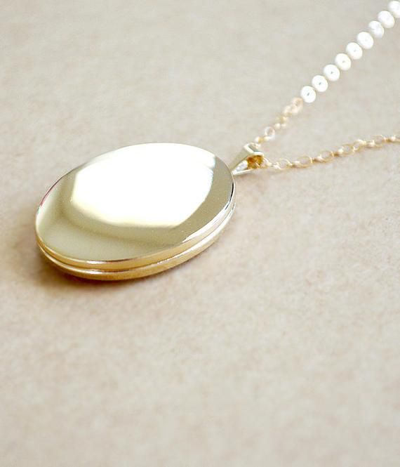 This large gold filled oval locket is a beautiful, classic piece of jewelry. This smooth, shiny finish is timeless and will be a lasting heirloom that can be worn and treasured throughout the wonderful moments of your life.•••••• ITEM DETAILS ••••••••••••••••••••••••••••••••••• Gold Filled locket measures 26 mm, approximately 1 inch• Photo inserts on both inside areas of the locket. (colored paper can be used as a guide for fitting/trimming photo)• 14K Gold Filled chain• Jump rings and clasps ar Classic Oval Locket Necklace Stamped 14k, Dainty Gold Oval Locket Necklace, Elegant Oval Link Locket Necklace, Elegant Gold Oval Pendant Locket Necklace, Dainty Gold Oval Pendant Locket Necklace, Elegant Oval Link Locket Necklace For Wedding, Elegant Oval Locket Necklace As A Gift, Elegant Oval Locket Necklace For Gift, Oval 14k Gold-filled Jewelry For Anniversary