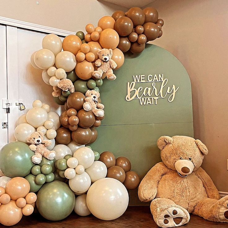 a teddy bear sitting on top of a wooden table next to balloons in the shape of a heart