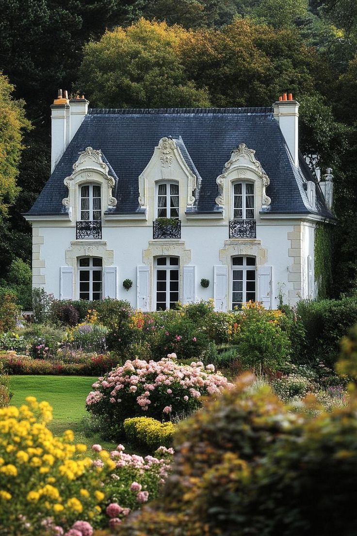 a large white house surrounded by flowers and trees