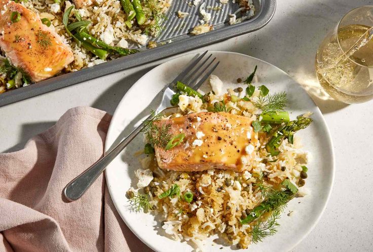 salmon and rice with asparagus on a plate next to a glass of wine