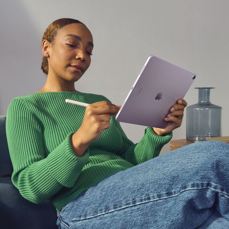 a woman sitting on a couch holding an apple laptop computer and looking at the screen