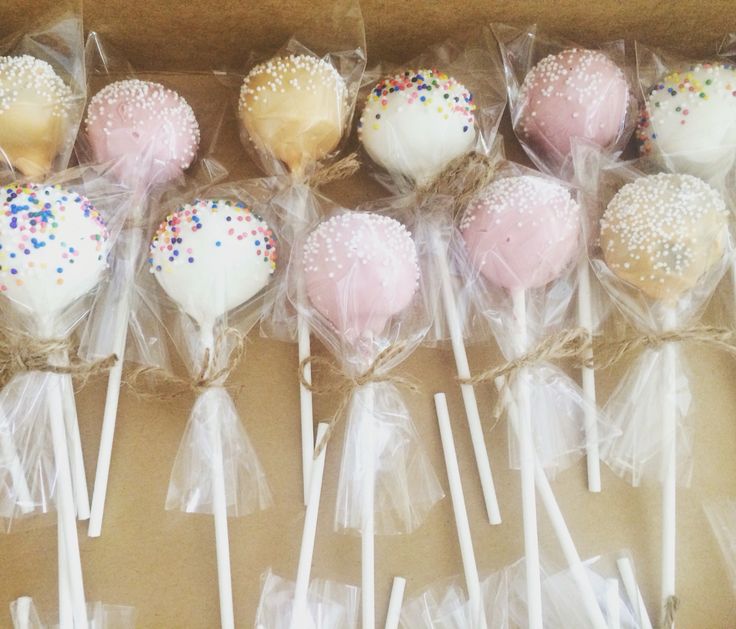 a box filled with cake pops covered in sprinkles and white frosting