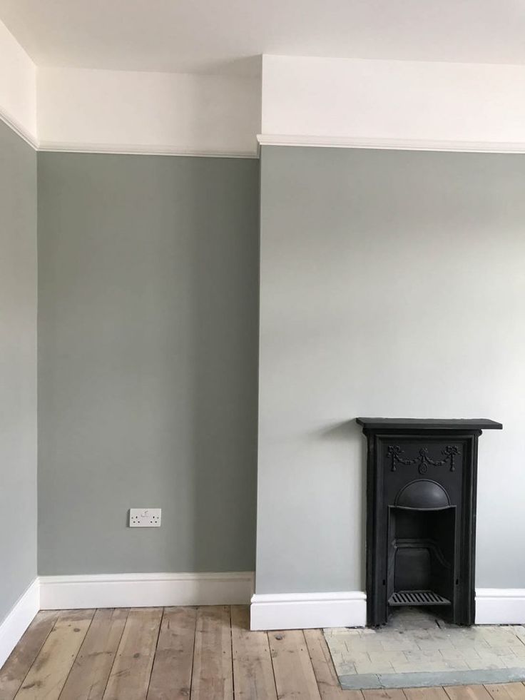 an empty room with a fireplace in the corner and hard wood flooring on the other side