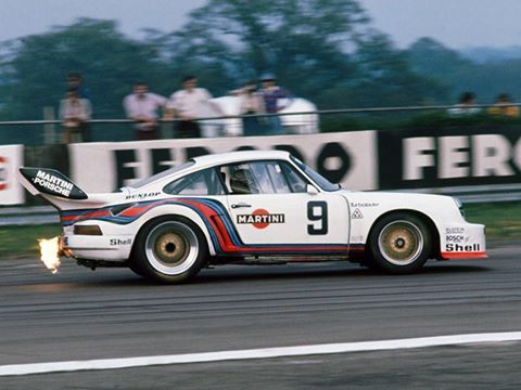 a white car driving down a race track with people watching from the sidelines behind it