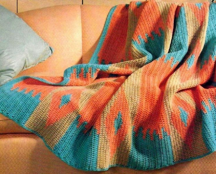 an orange and blue blanket sitting on top of a couch