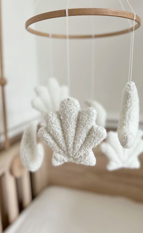 a crocheted mobile hanging from a wooden rod in a room with white walls