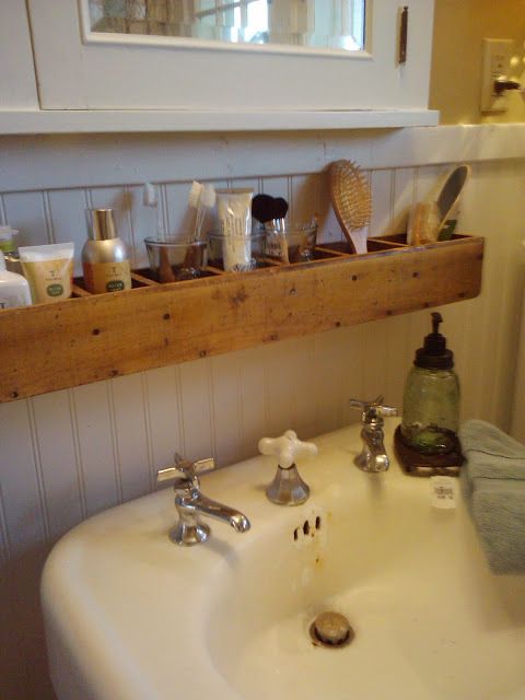 a white sink sitting under a window next to a wooden shelf filled with bathroom items