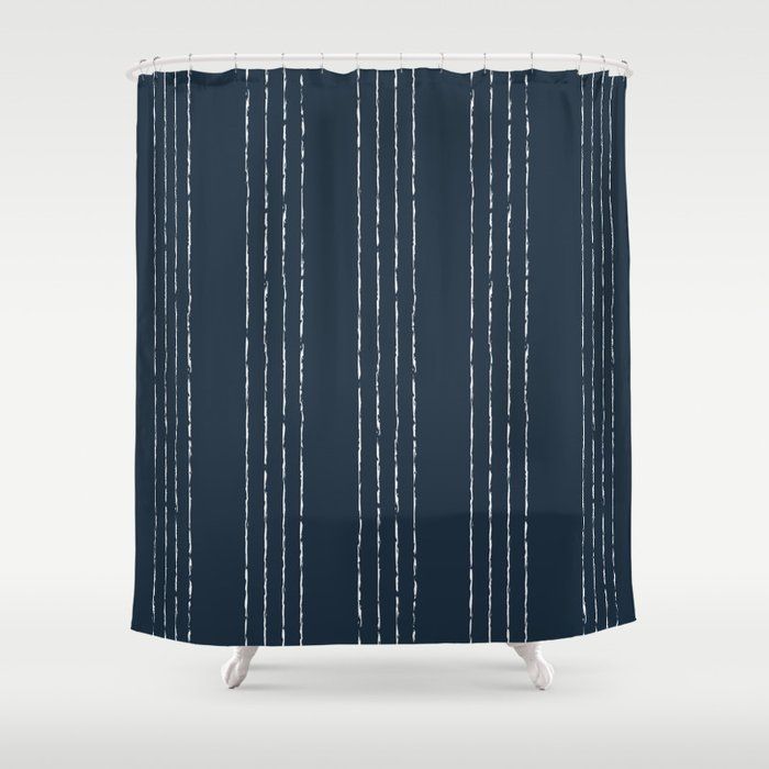 a dark blue shower curtain with white lines on the bottom and bottom, in front of a