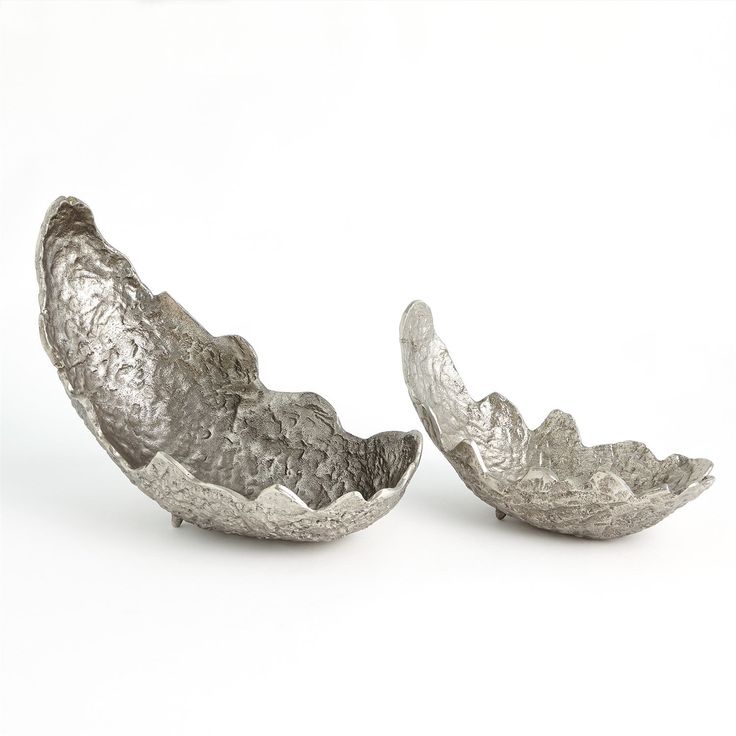 two metal bowls sitting side by side on a white surface