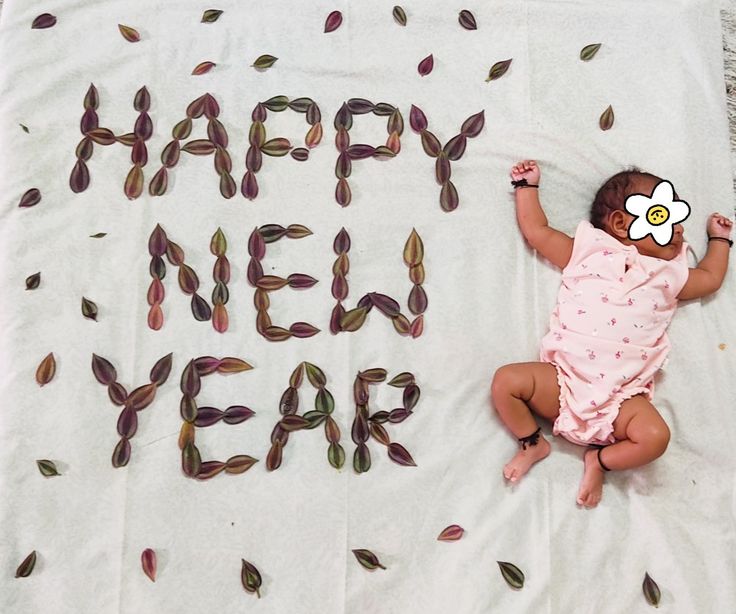 a baby laying on top of a blanket with the words happy new year written in it