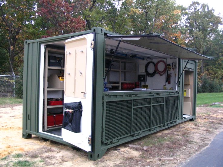 a green and white portable kitchen on the side of a road with trees in the background