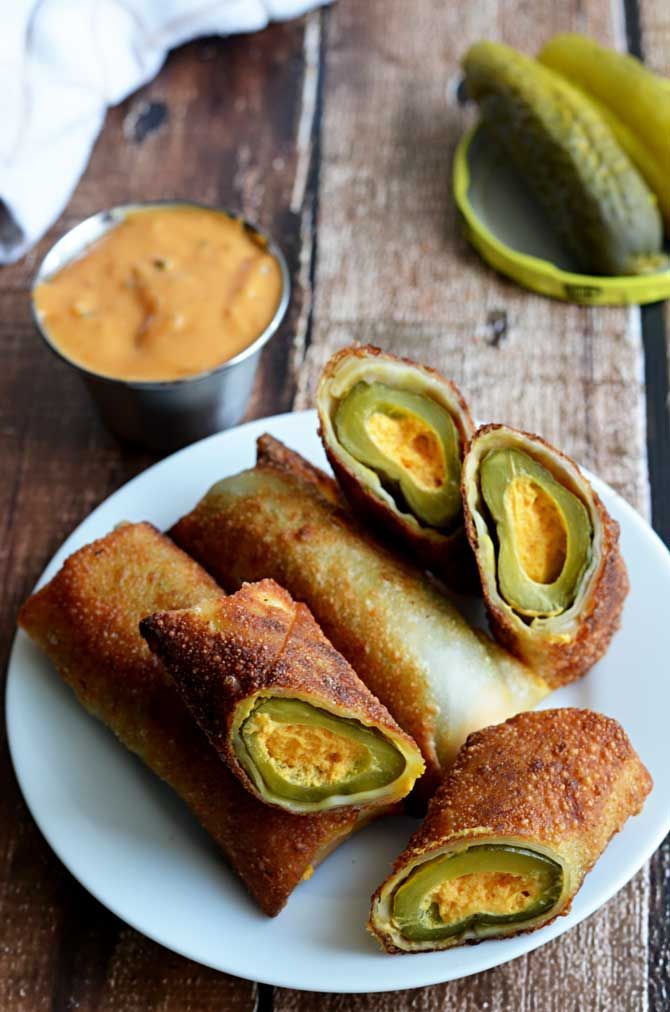 some food is on a white plate with sauces and pickles next to it