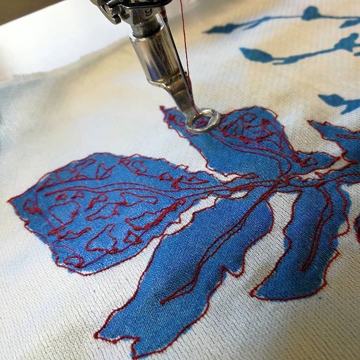 a close up of a sewing machine on a table cloth with blue and red designs