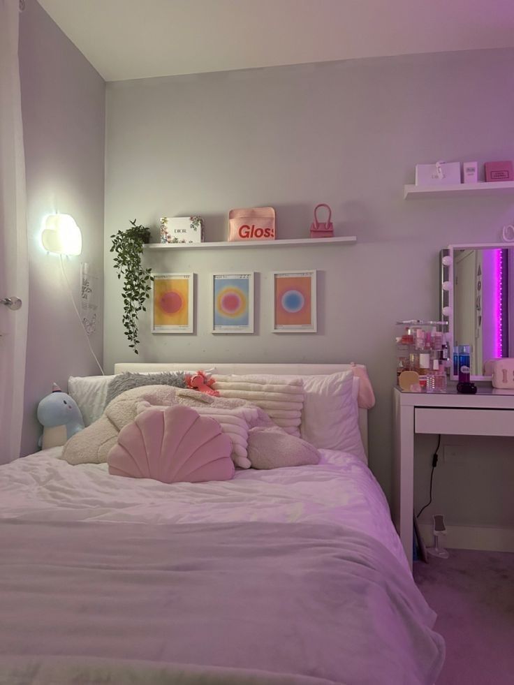 a white bed sitting under a purple light in a bedroom next to a desk and mirror