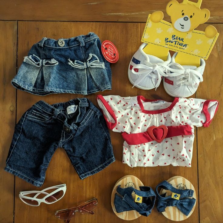 baby clothes and shoes are laid out on the floor next to a pair of sunglasses