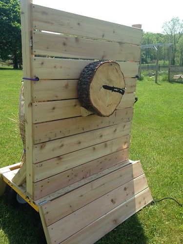 a wooden structure with a clock on it in the middle of a grassy area next to a fence