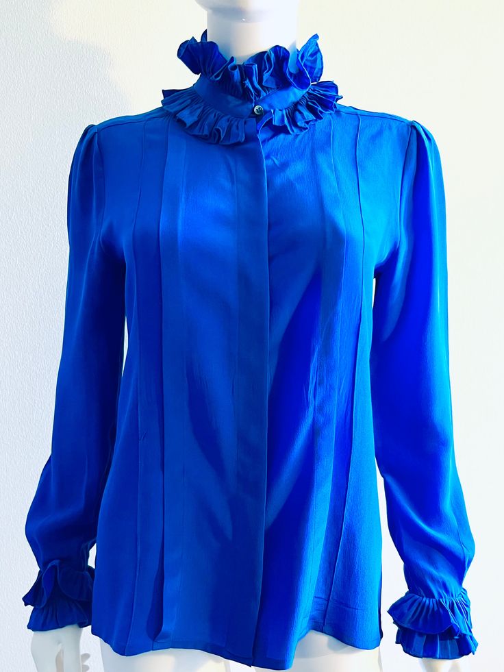 "Just beautiful butter soft, pure silk, royal cobalt blue blouse featuring double ruffles at the neckline and cuffs, pleating, and a front buttons closure under the placket.  Designer label removed. Approximate Measurements:     Chest: 38 1/2\"; Waist: 36 1/2\"; Length: 25\"     Labeled a size 6 Fabric: 100% silk Condition: Very good vintage condition, as shown." Classic Blue Silk Blouse, Elegant Blue Blouse With Pleated Sleeves, Blue Silk Formal Tops, Blue Long Sleeve Formal Blouse, Blue Long Sleeve Blouse For Formal Occasions, Formal Blue Silk Tops, Elegant Blue Blouse With Ruffled Collar, Formal Pleated Silk Blouse, Elegant Blue Top With Ruffled Collar