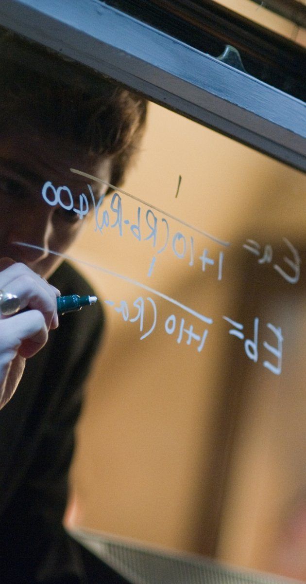 a young man writing on a white board